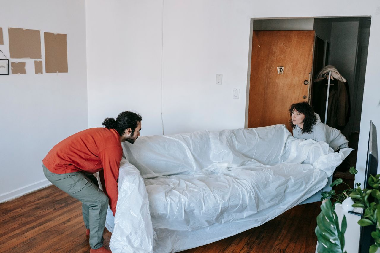 services-02 A couple collaboratively lifting a couch while moving into a new apartment.